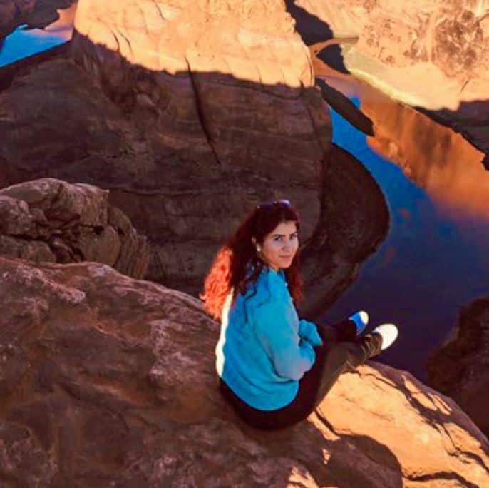 Melanie Gutierrez sitting on cliff in a Canyonland