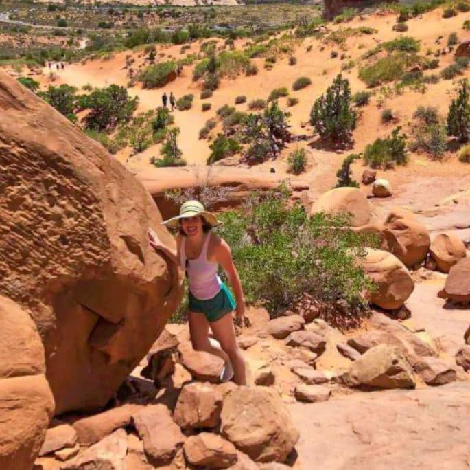 Meghan Hartigan travel picture in desert leaning on large rock