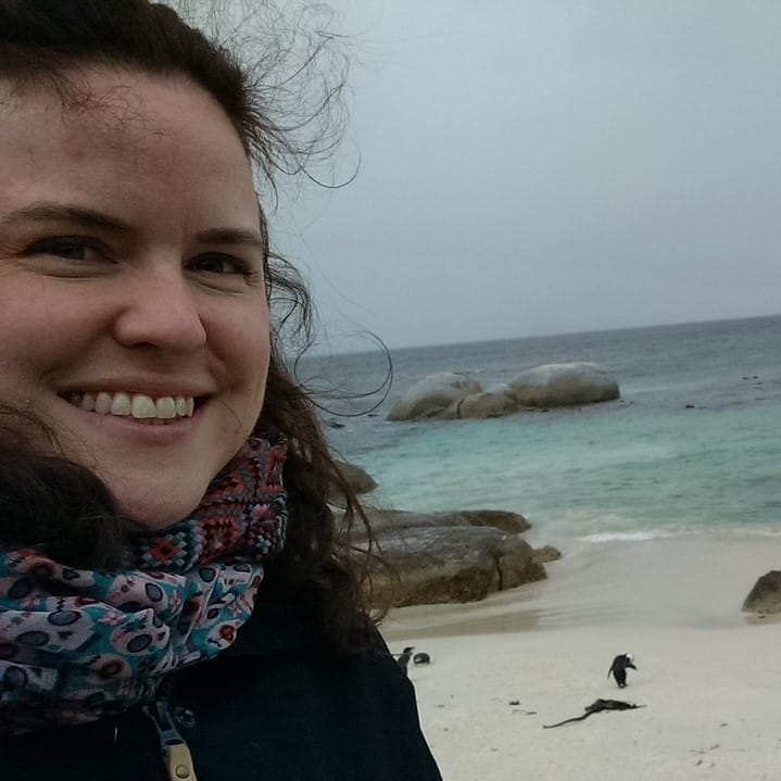 Emily Power with penguins on the beach