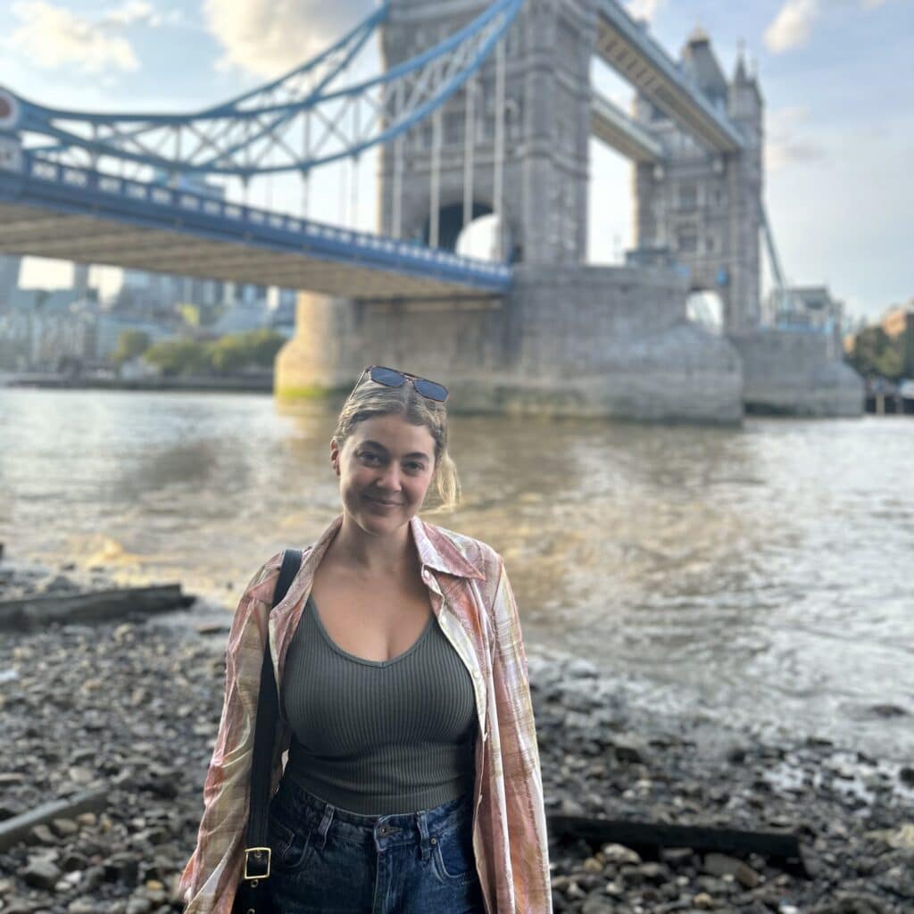 Evelyn Russo standing on the beach in front of a bridge