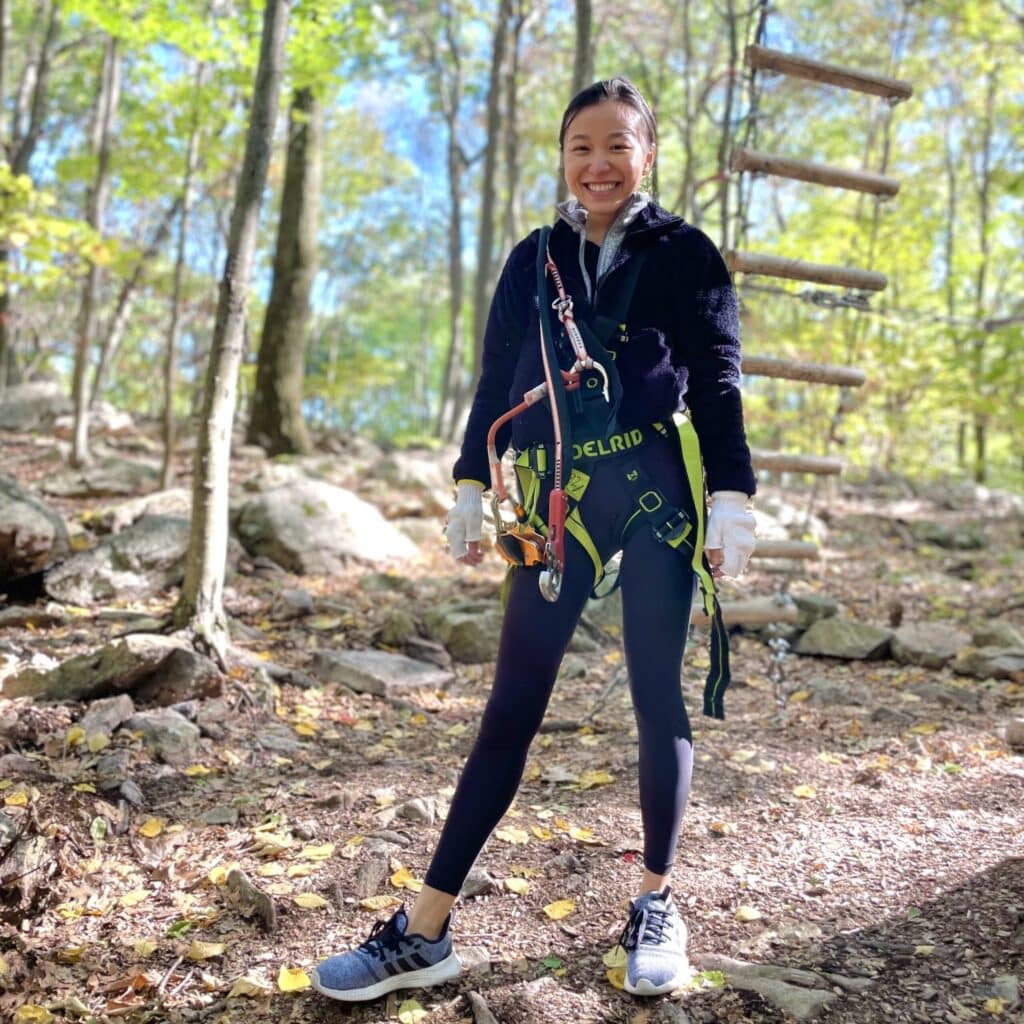 Gigi Chan in the woods with climbing gear on