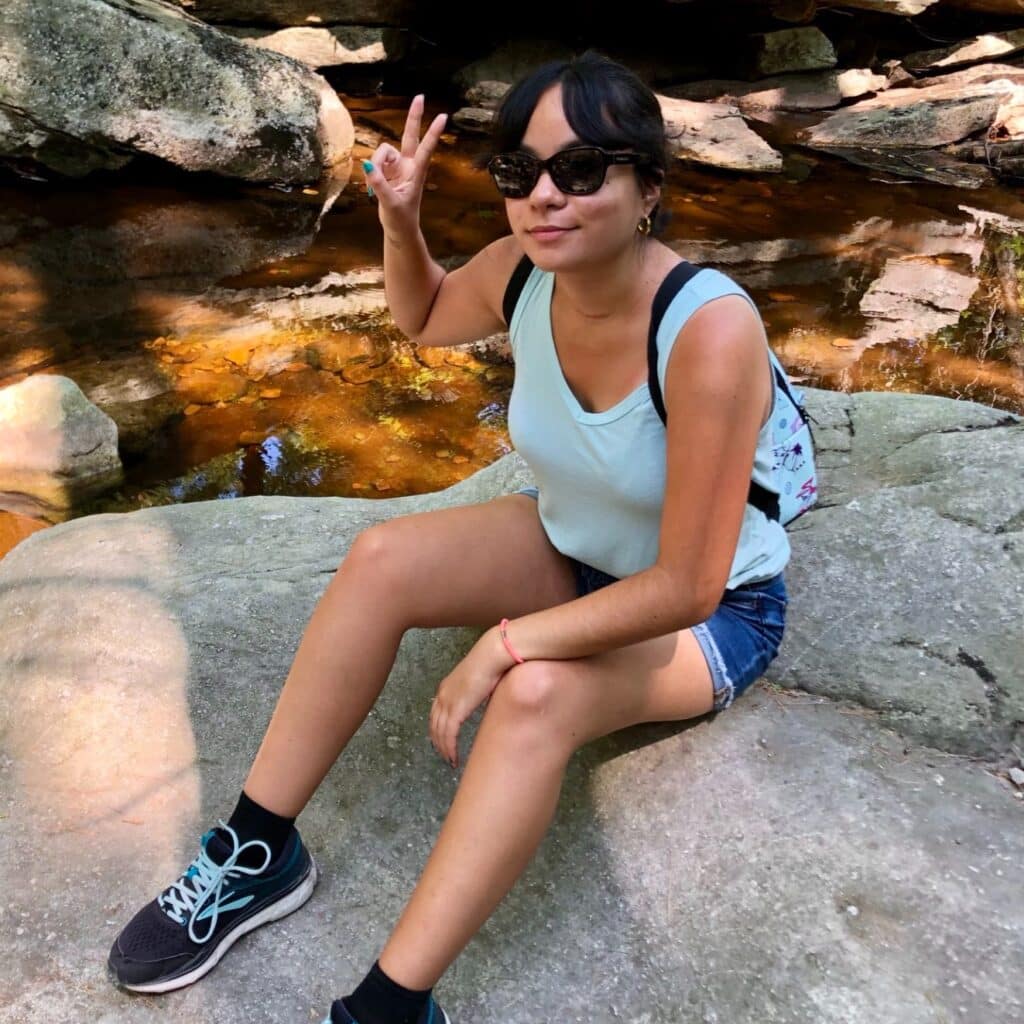 Kathleen Siano sitting on a rock in a river