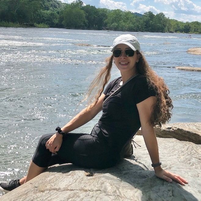 Mikayla Basil sitting on a rock by the beach