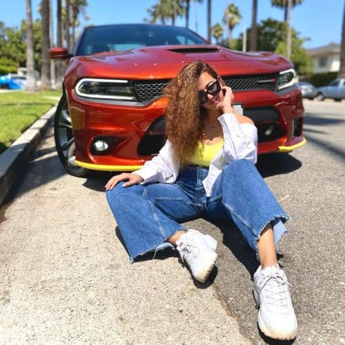 Simran Jaisinghani sitting in front of a car