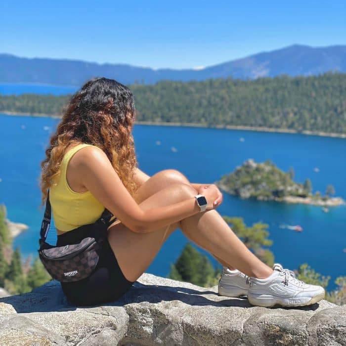 Simran Jaisinghani sitting on a rock in front of water