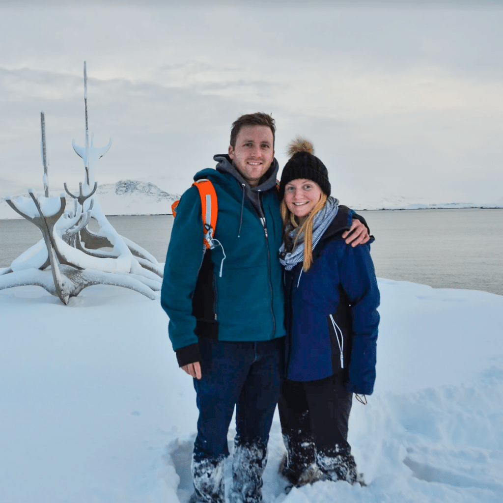 Zach Cogavin with a friend in front of viking ship sculpture after heavy snowfall