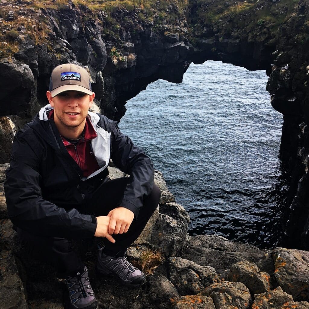 Benjamin Kraus hiking picture resting on front of sea arch