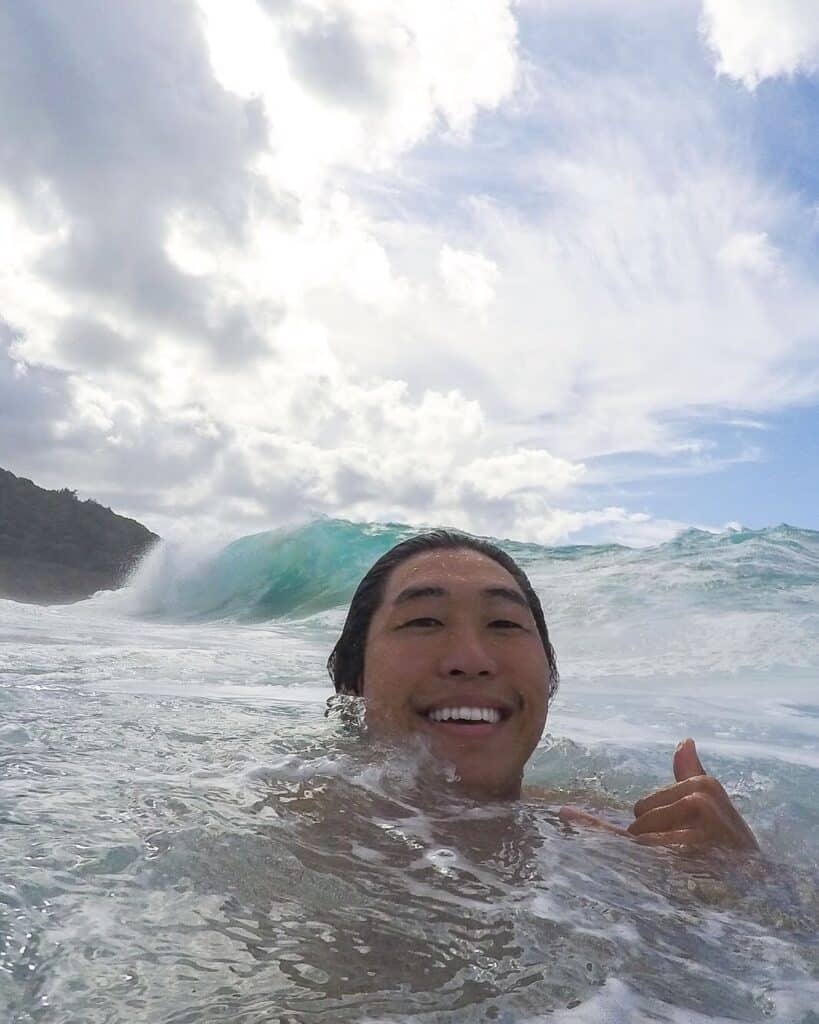 Colby Choi in shorebreak doing thumbs up