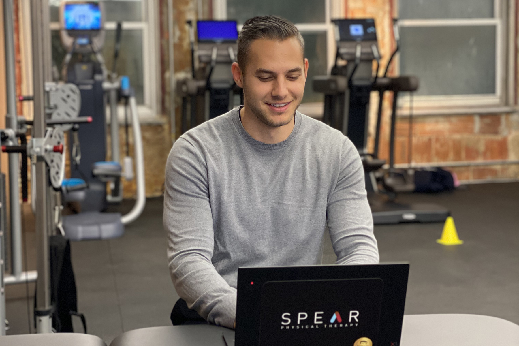 Physical Therapy instructor on laptop in gym