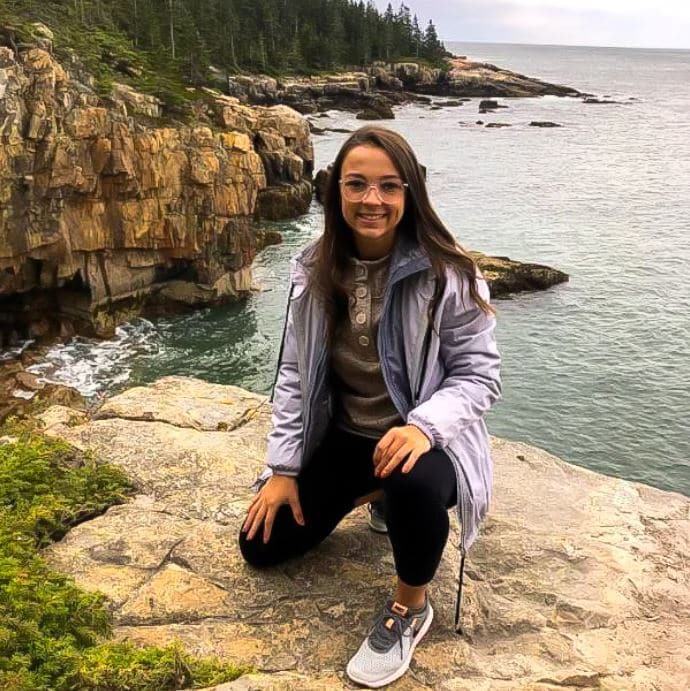 Kendra Barlotta kneeing on a cliff next to the sea