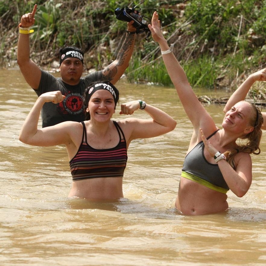 Kristen Markoe flexing muscles in river during spartan race