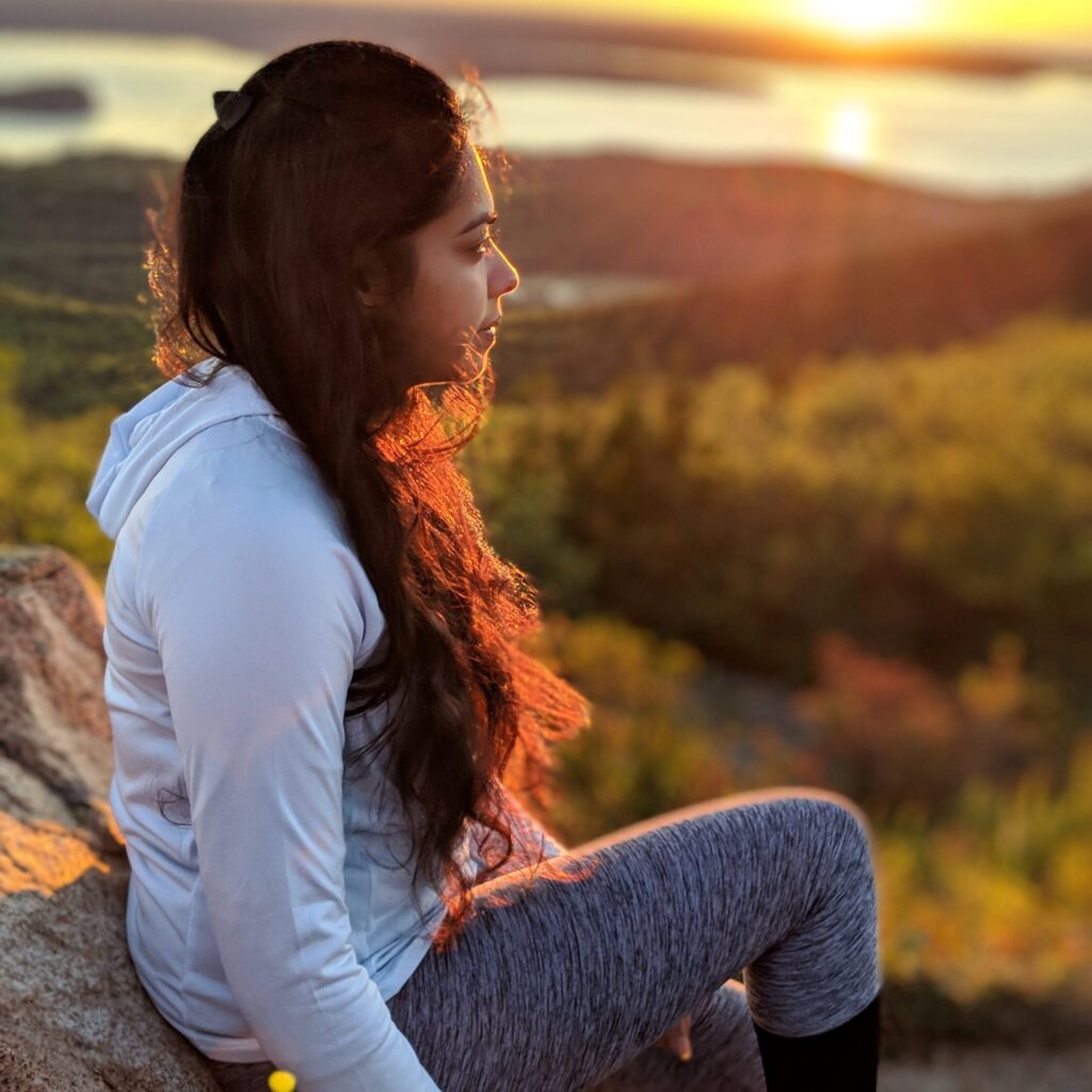 Aakanksha Bhagwat hiking picture overlooking forest in Autumn during sunset