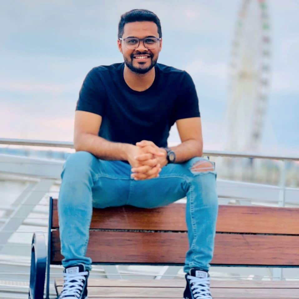 Anant Kulkarni sitting on a bench in front of ferris wheel