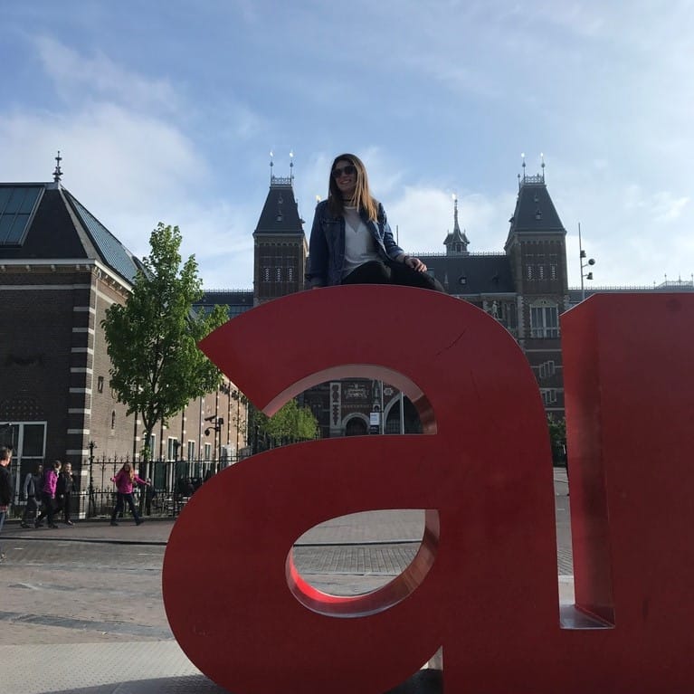 Ariel Scheintaub sitting on top of a letter A sculpture