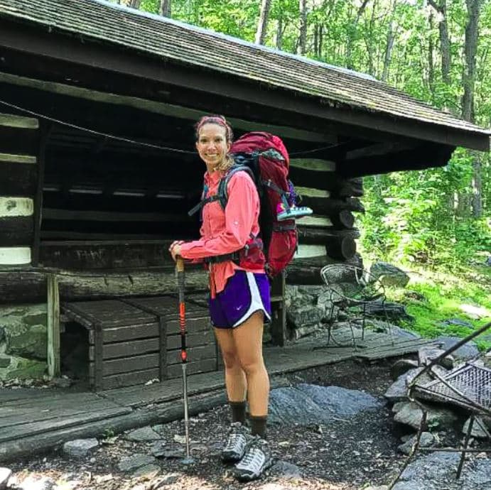 Molly Polizotto hiking, standing in front of hut