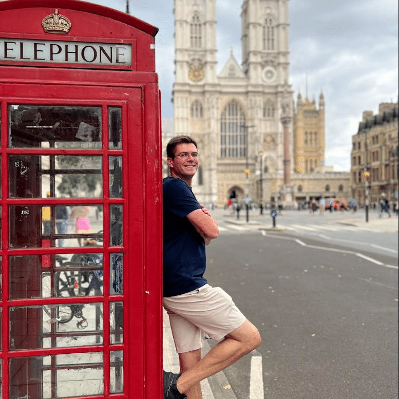 Jonathan Doyle travel portrait in England in front of church leading on red phone booth