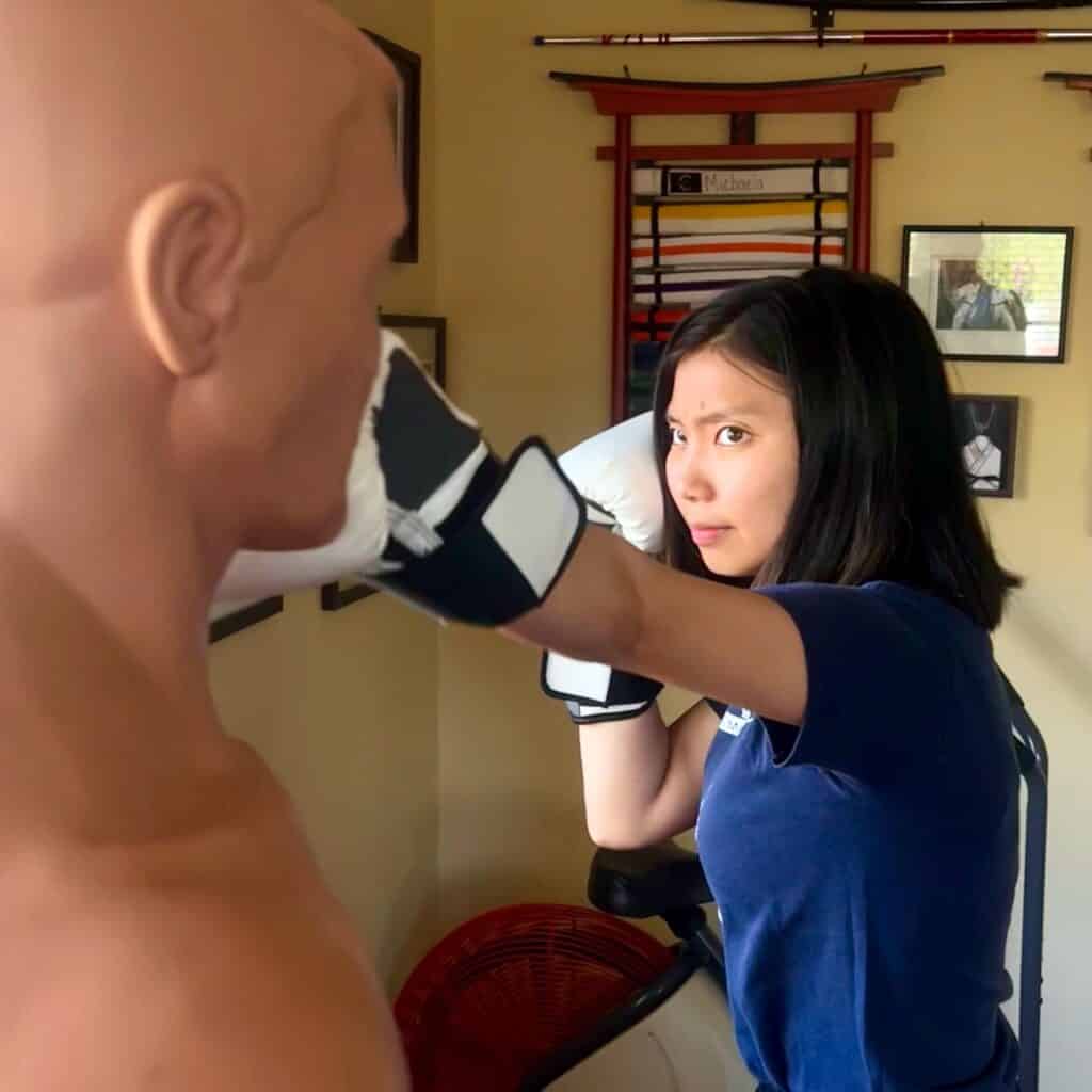 Michaela Chee boxing a practice dummy