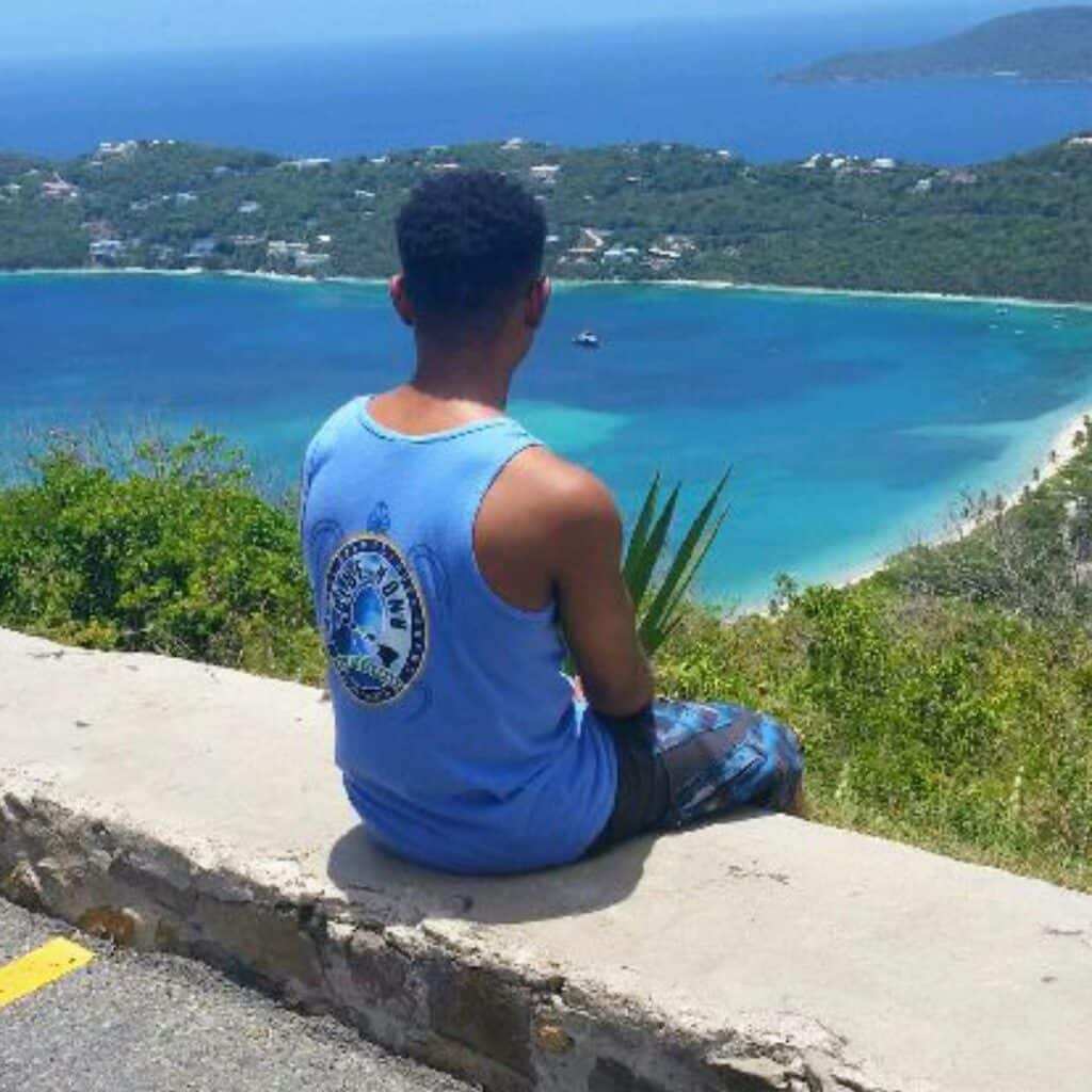 Nicholas Strickland sitting on ledge overlooking a bay