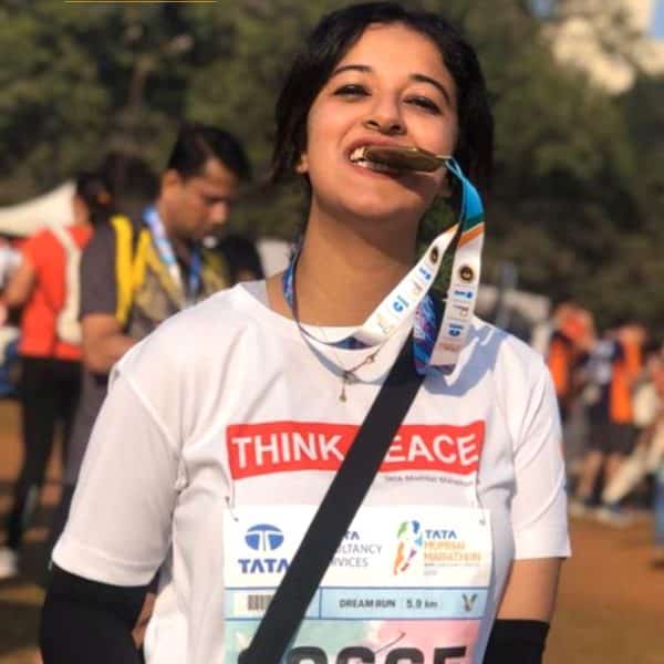 Simran Jaisinghani biting a medal after a race