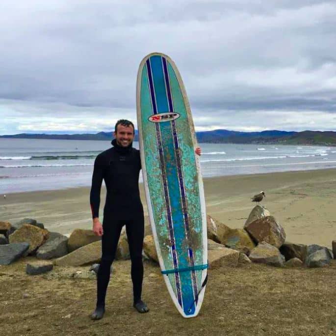 Matthew Procopio with surfboard on beach