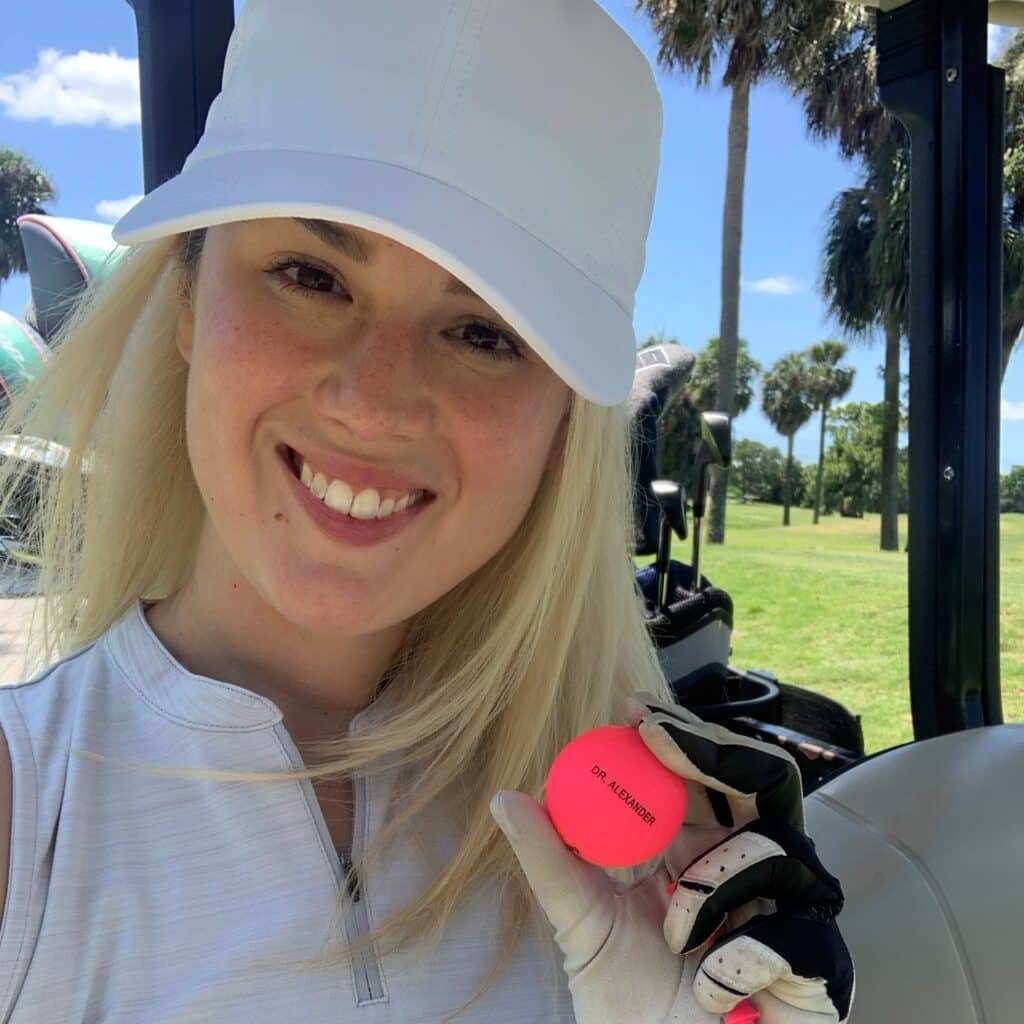 Tori Alexander holding golf ball in golf cart