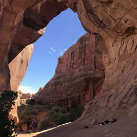 Elana Jonas resting under a rock Arch in Arches national park