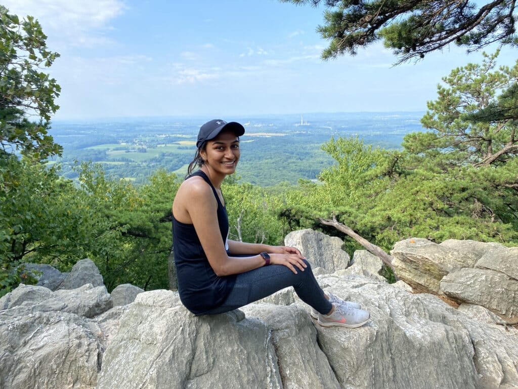 Kruti Shah hiking picture sitting on rock on mountain top