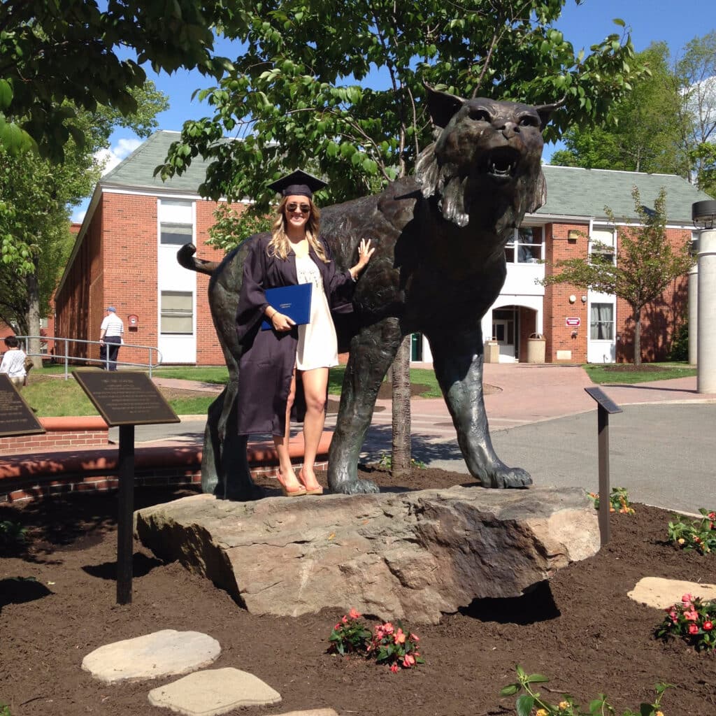 Kathleen O'Donnell-Pickert next to large lynx statue. Graduation picture.