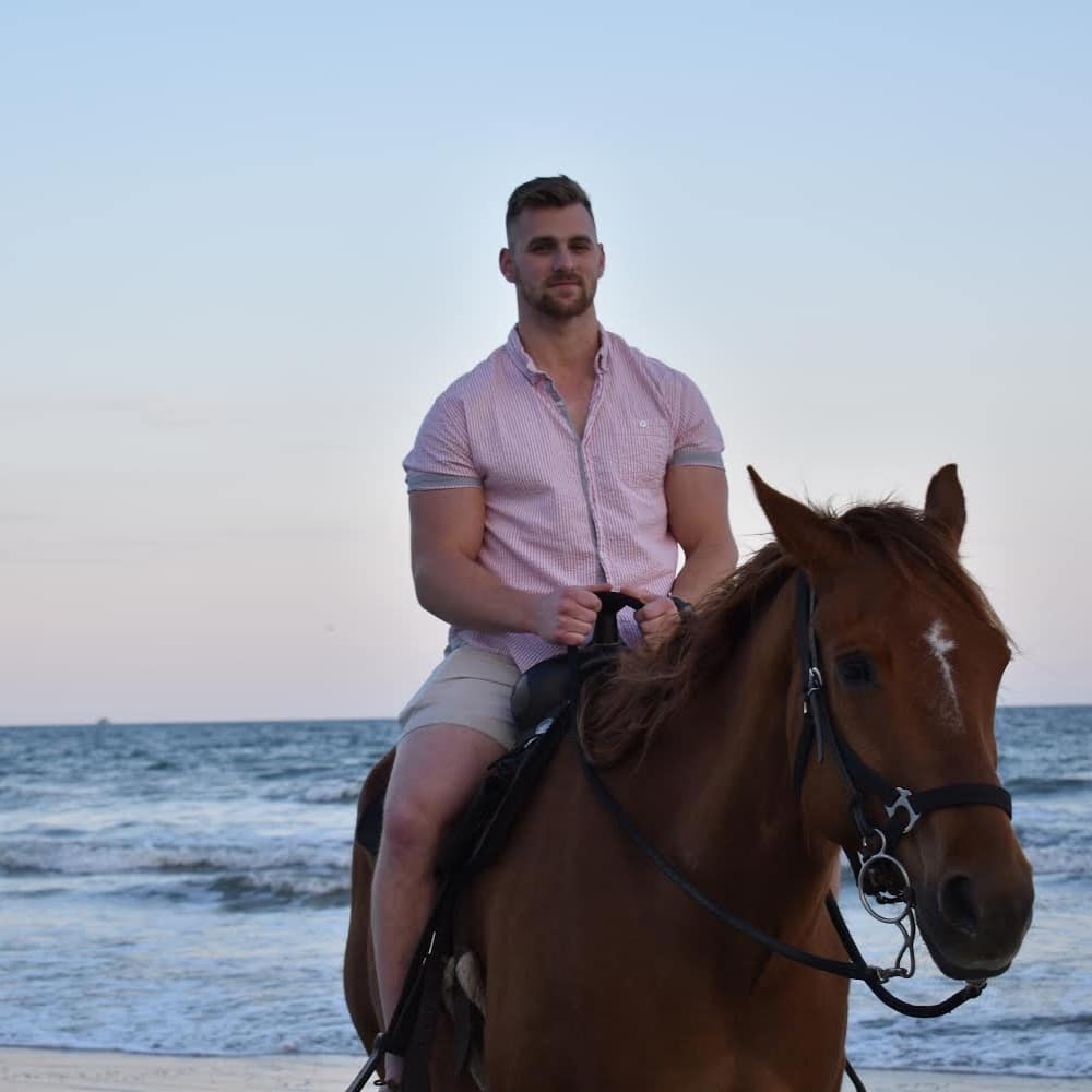 Jake Ober riding a horse on the beach