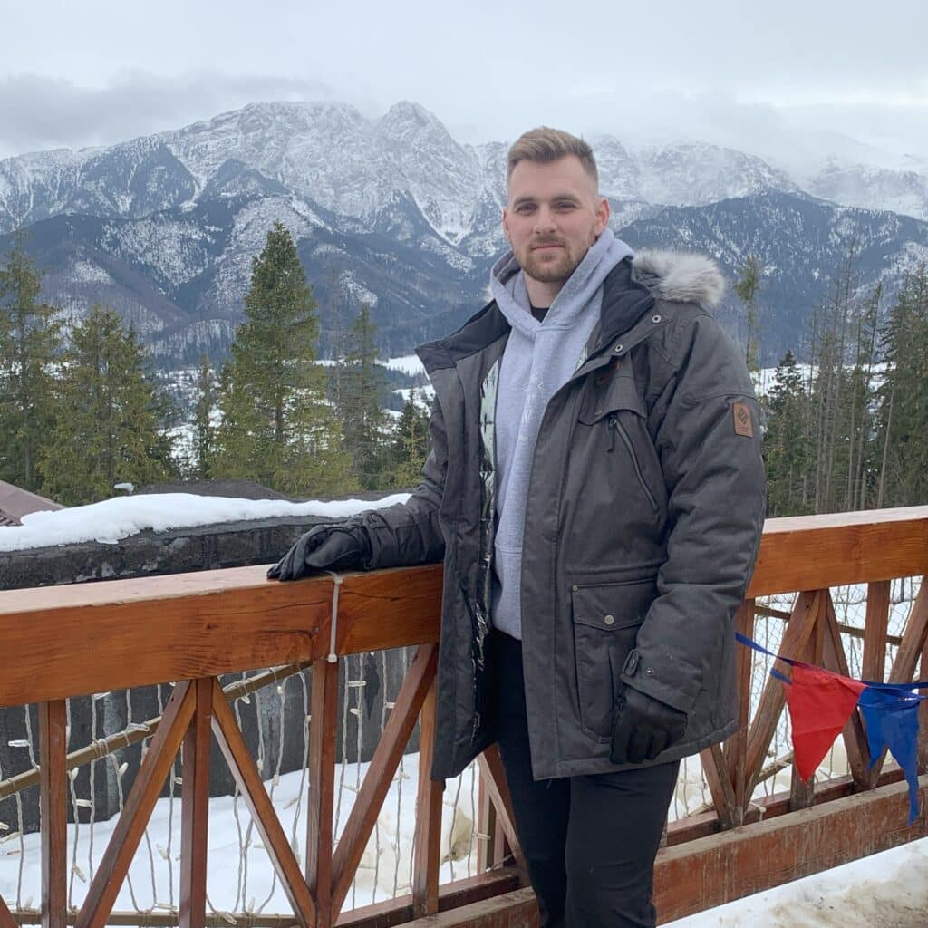 Jake Ober standing on a bridge in front of mountains