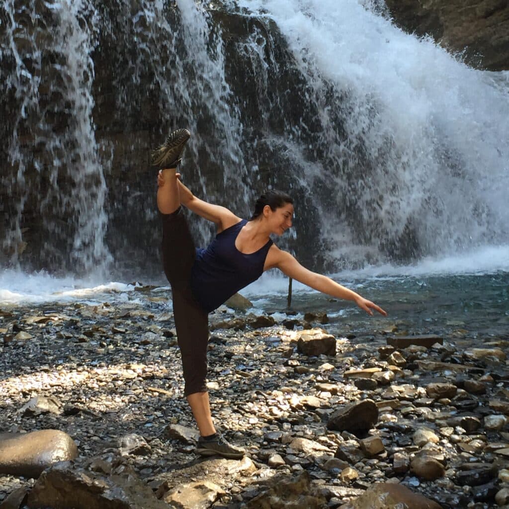 Elisabeth Miller doing Yoga in front of a waterfall