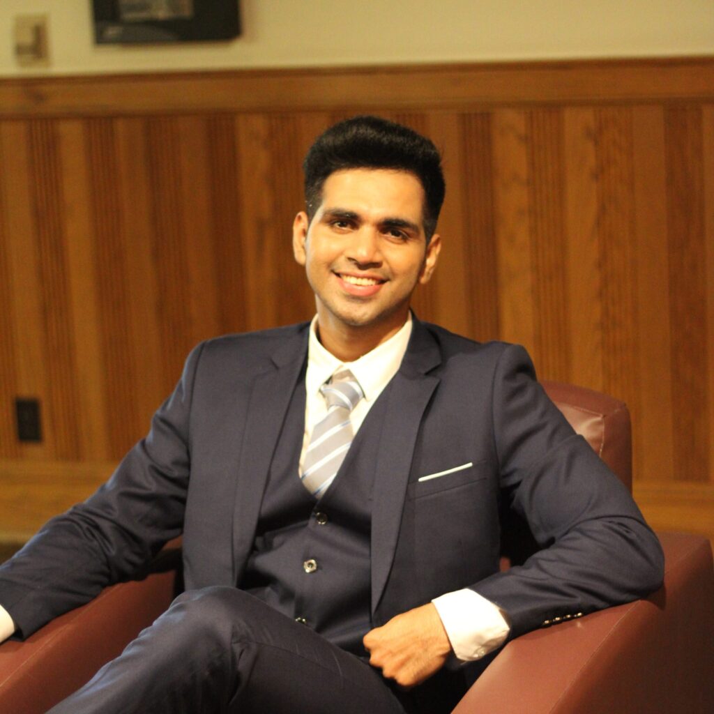 SHASHANK MISHRA sitting in a chair in a suit